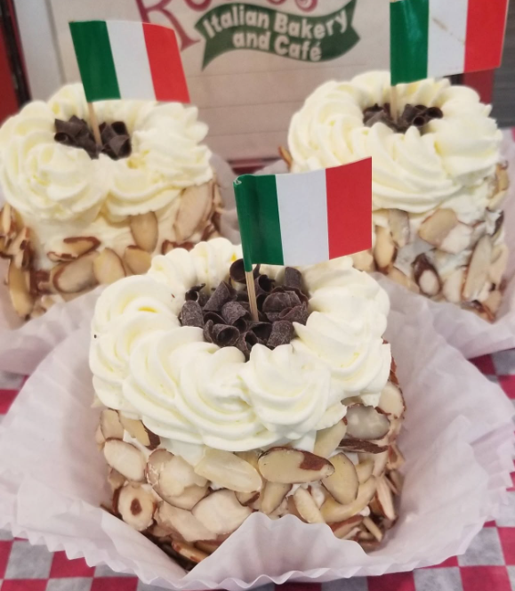 Mini almond cream cakes topped with whipped cream, chocolate chips and Italian flags